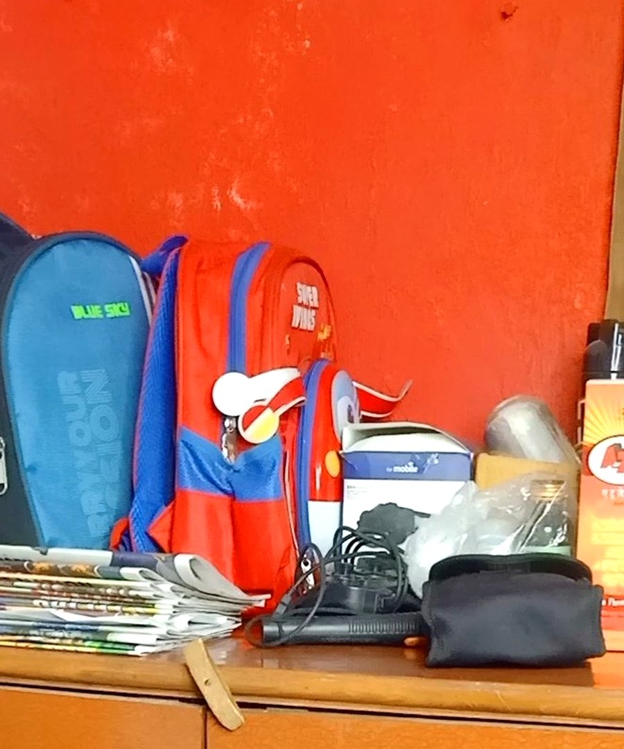 Family entryway desk before organizing — backpacks, magazines, cables, medicines, and miscellaneous items piled together