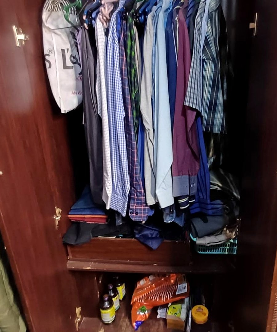 Men's formal wardrobe before organizing — shirts crammed on hangers, items scattered on lower shelf